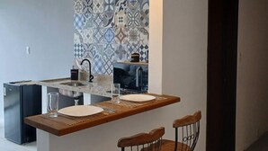 Een moderne keuken met een centraal kookeiland, twee barkrukken en hanglampen.