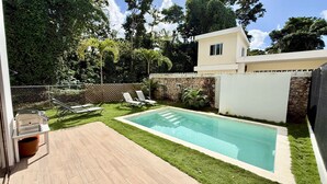 Ein Garten mit Swimmingpool, Grill und einer Steinmauer.