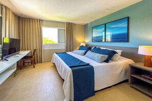 Ein Hotelzimmer mit Bett, Schreibtisch, Fernseher und einem Fenster mit Vorhängen.