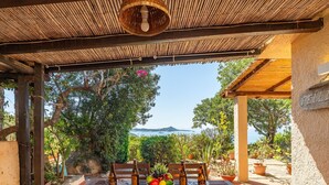 An outdoor dining area with a table set for two, surrounded by potted plants and a view of the sea. - Pellicano by Interhome (Villasimius)
