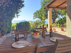A wooden table set for two with a bowl of fruit, two bottles of beer, and cutlery. - Pellicano by Interhome (Villasimius)