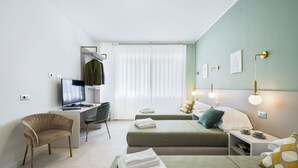 Une chambre d’hôtel moderne équipée d’un bureau, de deux lits, d’une chaise et d’un téléviseur.