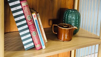 Une étagère en bois sur laquelle on aperçoit un appareil électroménager blanc, des livres, une tasse et des objets décoratifs.