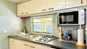 Une cuisine avec des meubles blancs, une cuisinière à gaz, un four à micro-ondes et une fenêtre donnant sur un paysage verdoyant.