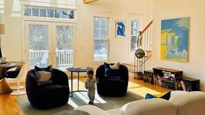 A spacious living room with a large sofa, two armchairs, a small table, and a bookshelf. - August or weekly rental bike to beach, walk to tennis! (Westerly)