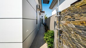 A narrow outdoor corridor with a stone wall on one side and a white building on the other. - 2Bdrm with Salt Water Pool 15 mins drive from Center (Krong Siem Reap)