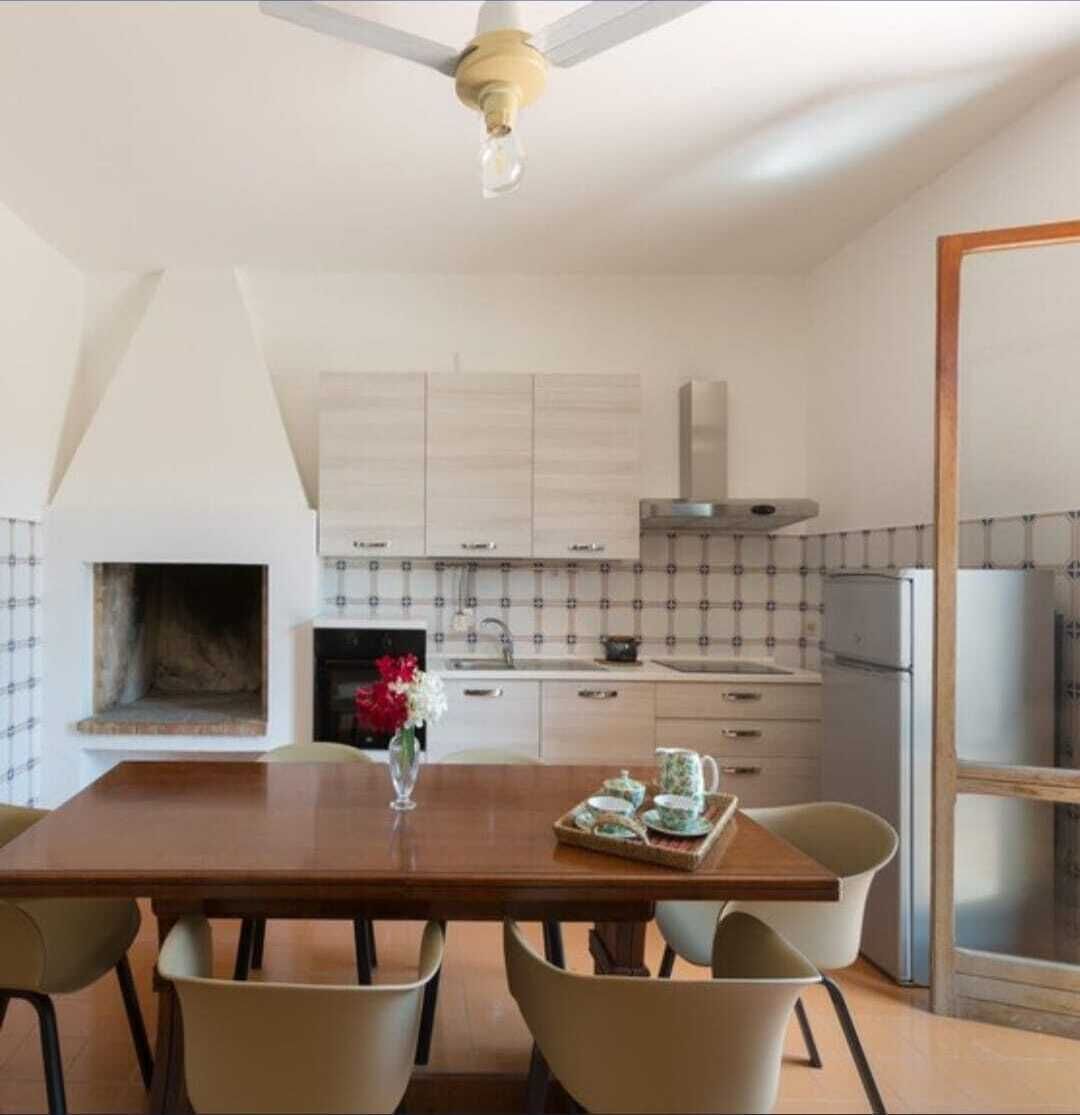 A modern kitchen with white cabinets, a built-in oven, and a dining area with a wooden table and four chairs.