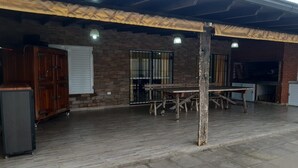 En udendørs patio med en murstensvæg, et træbord og et metal skab.
