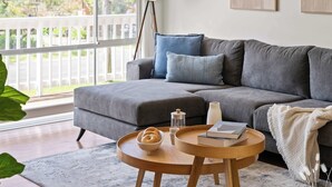 A living room with a grey sofa, a round wooden coffee table, and a floor lamp. - Kangaroo Sanctuary (Sanctuary Point)