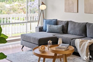 A living room with a grey sofa, a round wooden coffee table, and a floor lamp. - Kangaroo Sanctuary (Sanctuary Point)