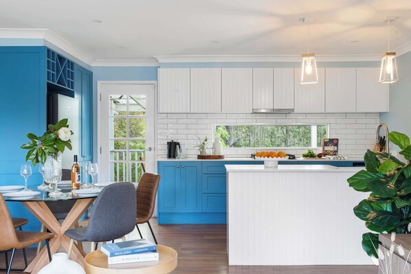 A modern kitchen with blue cabinets, a white island, and pendant lighting. - Kangaroo Sanctuary (Sanctuary Point)