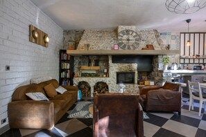 A cozy living room with a stone fireplace, a television, and a bookshelf.