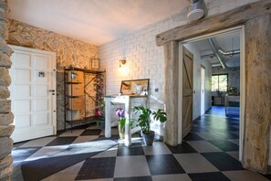 A hotel lobby with a stone wall, a checkered floor, a white reception desk, and a wooden door. - Bed & Breakfast “La Lisière” with Mountain View, Wi-Fi and Air Conditioning (Brantes)