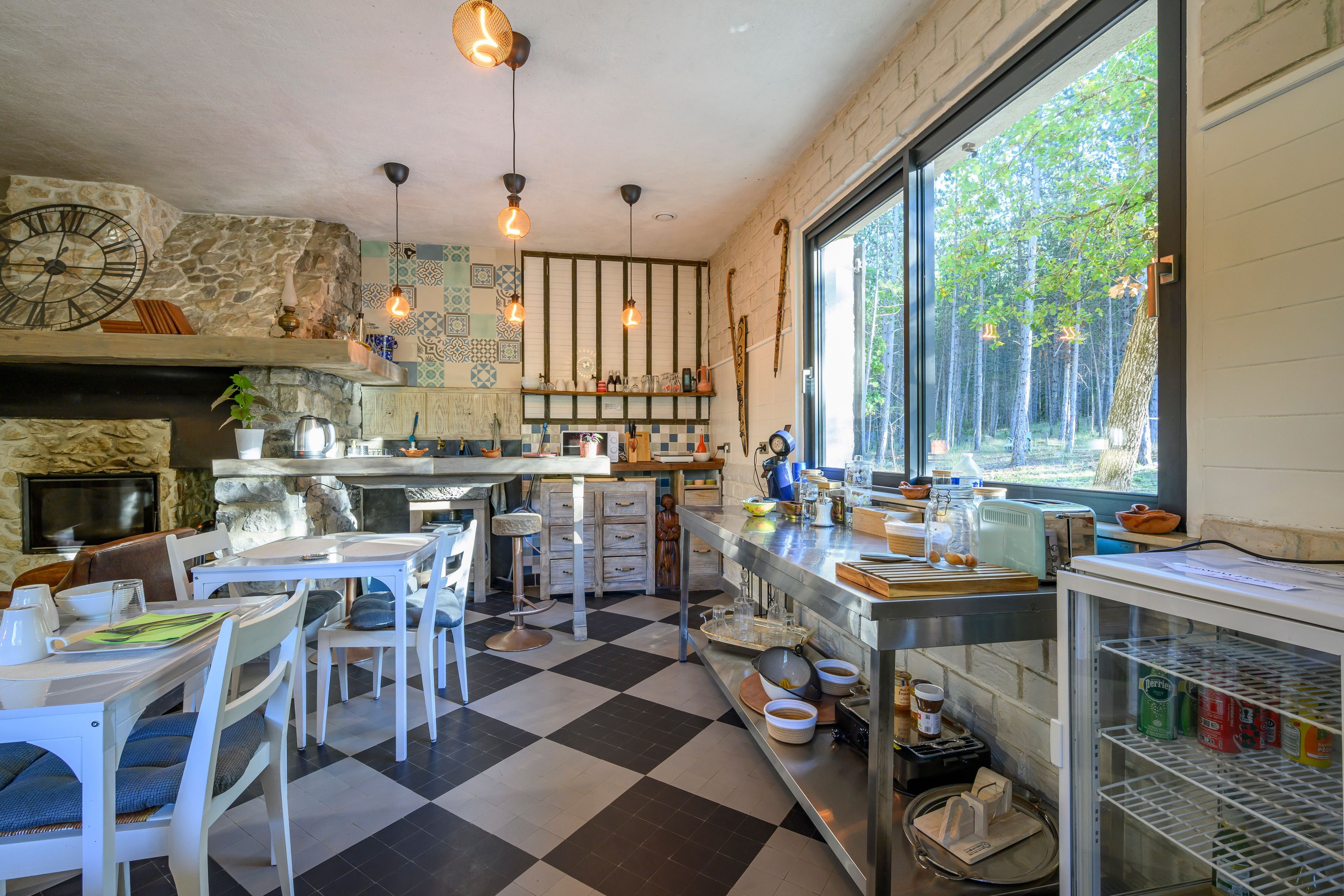 Una cocina con suelo a cuadros, pared de piedra y un amplio ventanal con vistas a un bosque.