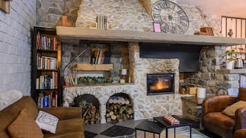 A cozy living room with a stone fireplace, bookshelves, and leather furniture.
