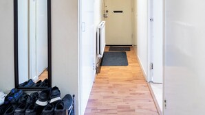 Ein Flur mit Holzboden, einem Spiegel links und einer Tür am Ende.