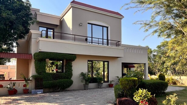 A modern two-story house with a paved driveway, a balcony, and various potted plants. - 3-bedroom farmhouse in outskirts of Mohali with AC comfort (Kurali)