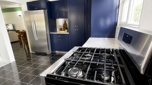 A modern kitchen with a stainless steel stove, blue cabinets, and a refrigerator. - Clifton House -Falmouth, Antigua - 3 Bed 2 Bath (St. Paul's)