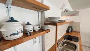 A kitchen with wooden shelves, white tiles, a stainless steel sink, and various kitchenware. - Apartment Entenbrücke - quiet & close to Stuttgart (Wendlingen am Neckar)