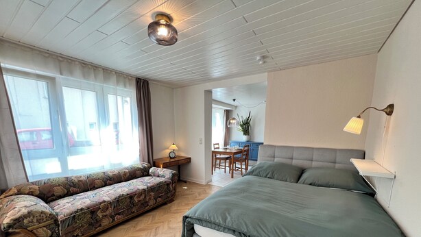 A bedroom with a bed, a sofa, a desk, and a dining table. - Apartment Entenbrücke - quiet & close to Stuttgart (Wendlingen am Neckar)