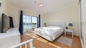 A bedroom with a bed, a TV, a desk, a nightstand, and a view of the outside. - B85 - Seasun Step Apartment in Praia da Rocha (Portimão)