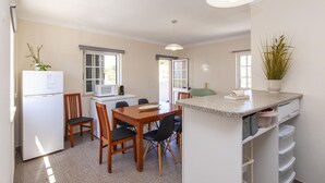 A compact kitchen with a dining table, chairs, a refrigerator, a microwave, and a small island with storage. - A76 - Casa da Ponte Duplex in Lagos (Lagos)