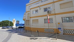 A building with a checkered pattern on the lower facade, a stop sign, and a signboard with text. - B83 - Calheta Terrace View Apartment (Lagos)