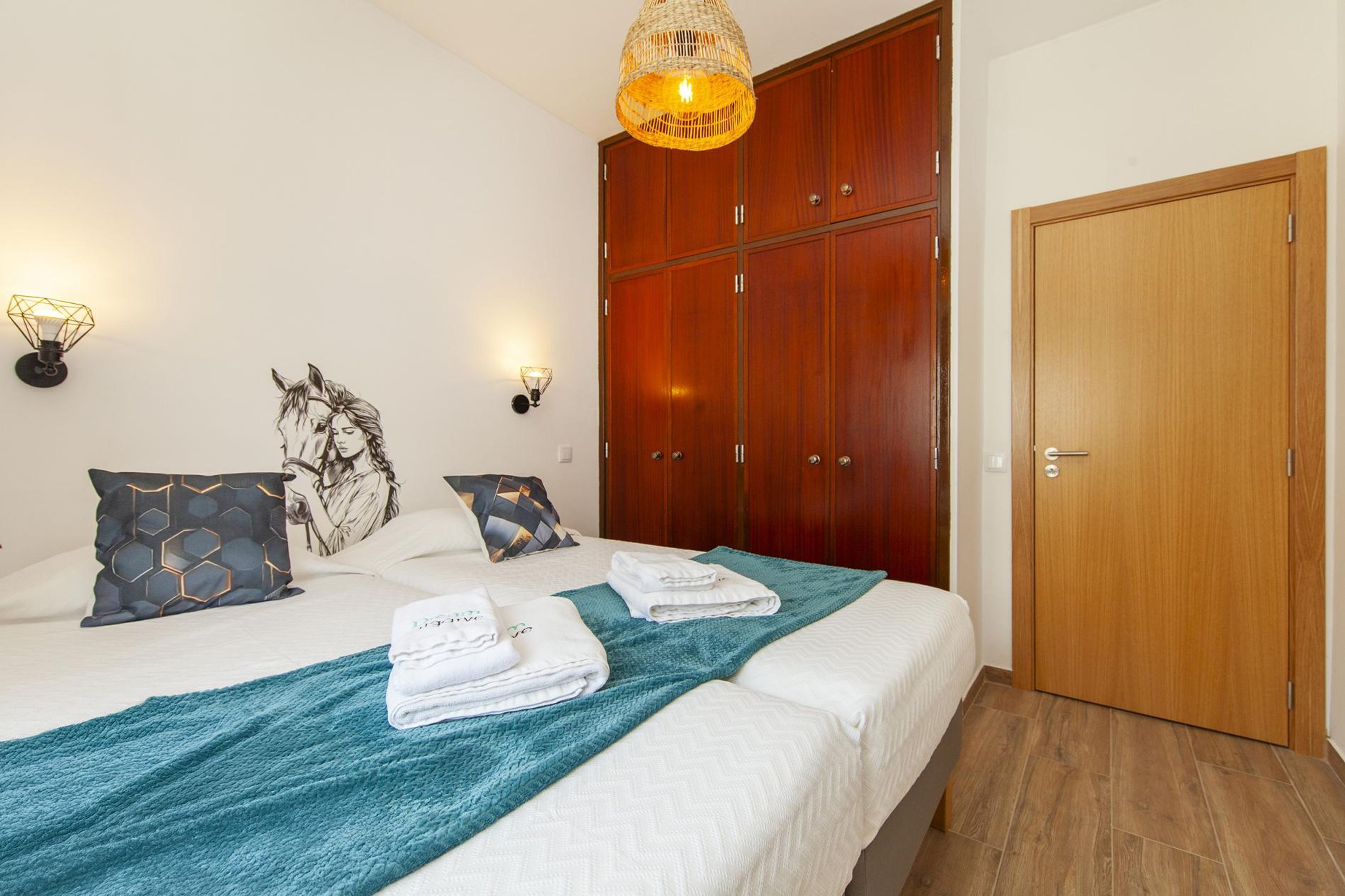 A hotel room with a bed, a wardrobe, and a door.