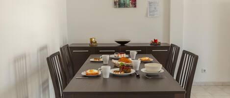 Un comedor con una mesa larga dispuesta para una comida, rodeada de sillas.