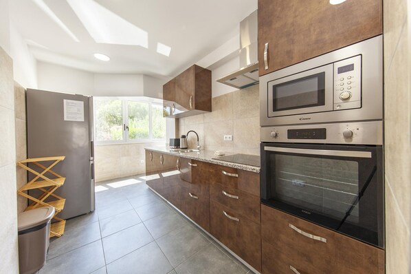 Una cocina moderna con electrodomésticos de acero inoxidable, armarios de madera y un amplio ventanal que proporciona luz natural.