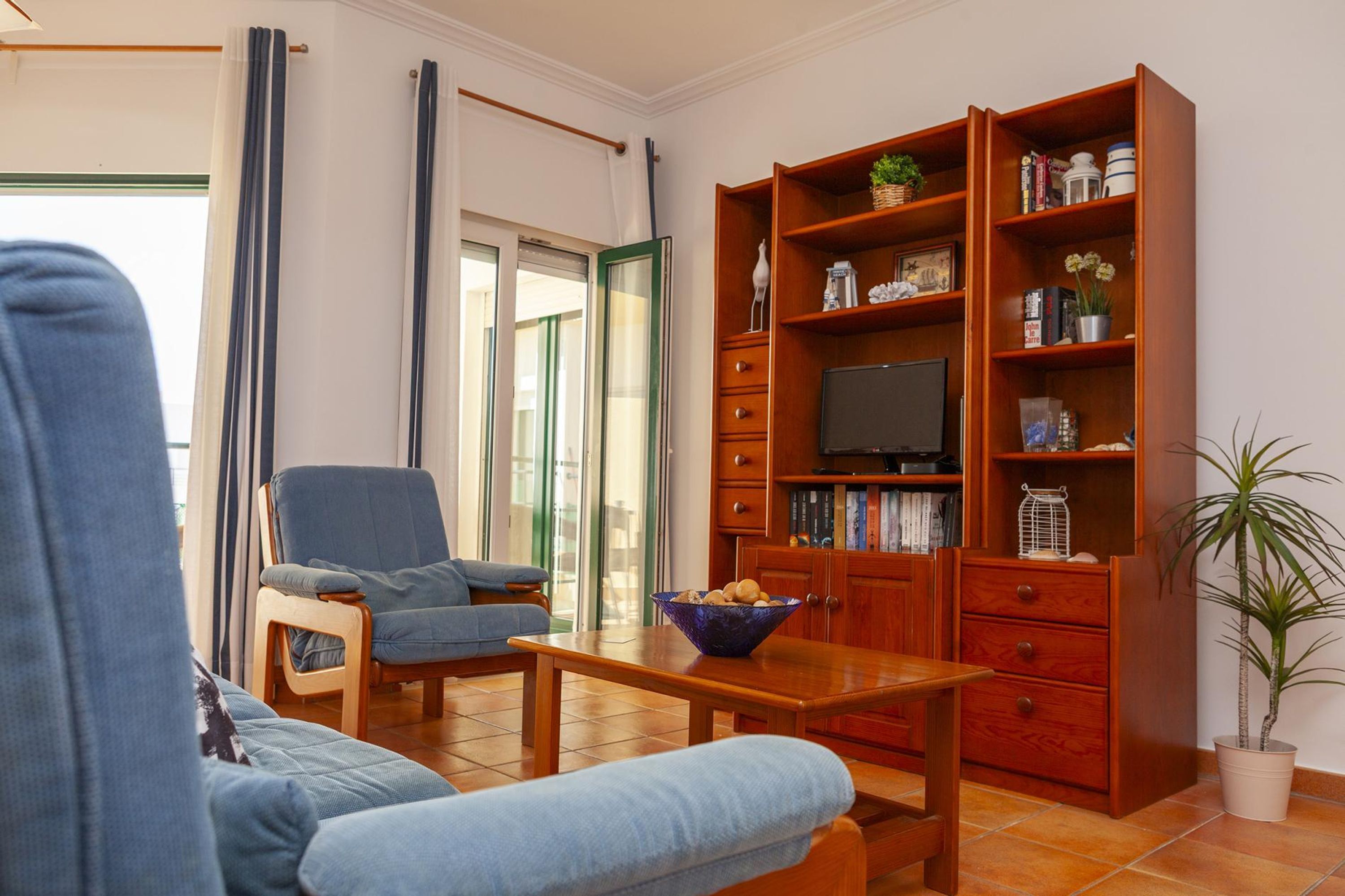 A living room with a sofa, armchair, wooden coffee table, and a bookshelf.