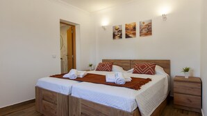 Un letto matrimoniale con testiera in legno, due cuscini e una coperta. Due lampade a parete e due quadri sopra il letto.