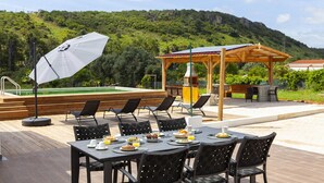 Un'area pranzo all'aperto con tavoli e sedie, una piscina e un gazebo.