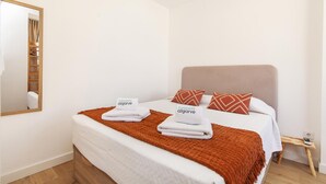 A bedroom with a bed, two pillows, a bedside table, a mirror, and a wooden floor. - B93 - Miralvor 2 Bed Apartment in Alvor (Portimão)