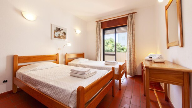 A room with two wooden beds, a desk, a chair, a mirror, and a window with curtains. - N 04 - Bedroom 4 in Amaro Sight Guesthouse (Lagos)