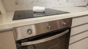 A kitchen with a built-in induction cooktop, stainless steel oven, and a marble backsplash. - B101 - Abrotea Cozy 2 Bed Apartment in Lagos (Lagos)
