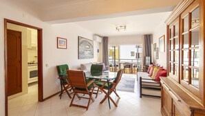 A spacious living area with a dining table, chairs, a sofa, and a cabinet. - A02 - Casa Topazio in Quarteira (Loulé)
