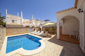 A swimming pool with lounge chairs, a stone wall, and a covered patio area. - FF 02 - Bedroom 2 in Sea Breeze Guesthouse (Lagos)