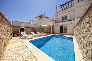 A swimming pool with lounge chairs, stone walls, and a covered patio area. - FF 02 - Bedroom 2 in Sea Breeze Guesthouse (Lagos)