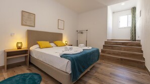 Ein Schlafzimmer mit einem Bett, Nachttischen, einem blauen Teppich und einer Treppe.