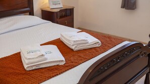 A neatly made bed with folded towels and a bedside table with a lamp and a sign. - FF 03 - Bedroom 3 in Sea Breeze Guesthouse (Lagos)