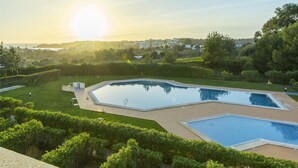 A swimming pool with a sunlit sky and distant buildings. - B01 - Mar a Vista Rocha Apartment (Portimão)