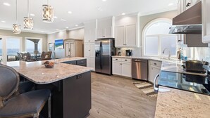 Una cocina moderna con encimeras de granito, electrodomésticos de acero inoxidable y una isla grande con asientos.