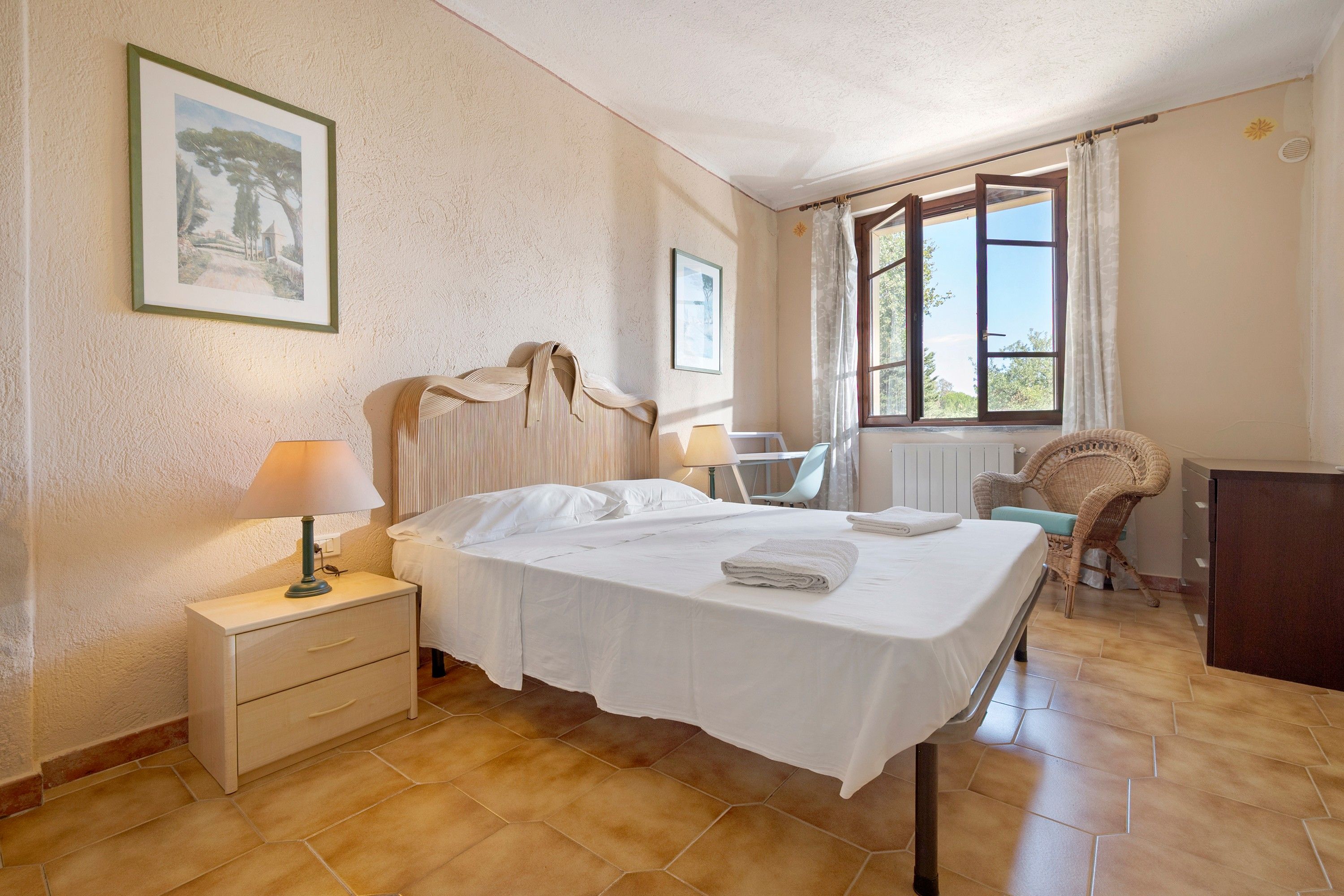 A hotel room with a bed, a desk, a chair, and a window with curtains.