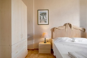 Ein Schlafzimmer mit einem Bett, einem Nachttisch, einer Lampe, einem Kleiderschrank und einem gerahmten Bild an der Wand.