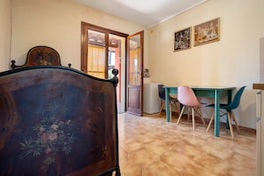 Une pièce comprenant un lit en bois, une table à manger avec des chaises et un réfrigérateur.