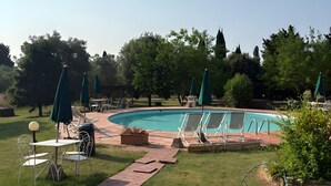 En trädgård med en pool, en uteplats med bord och stolar samt en trädgårdsdel.