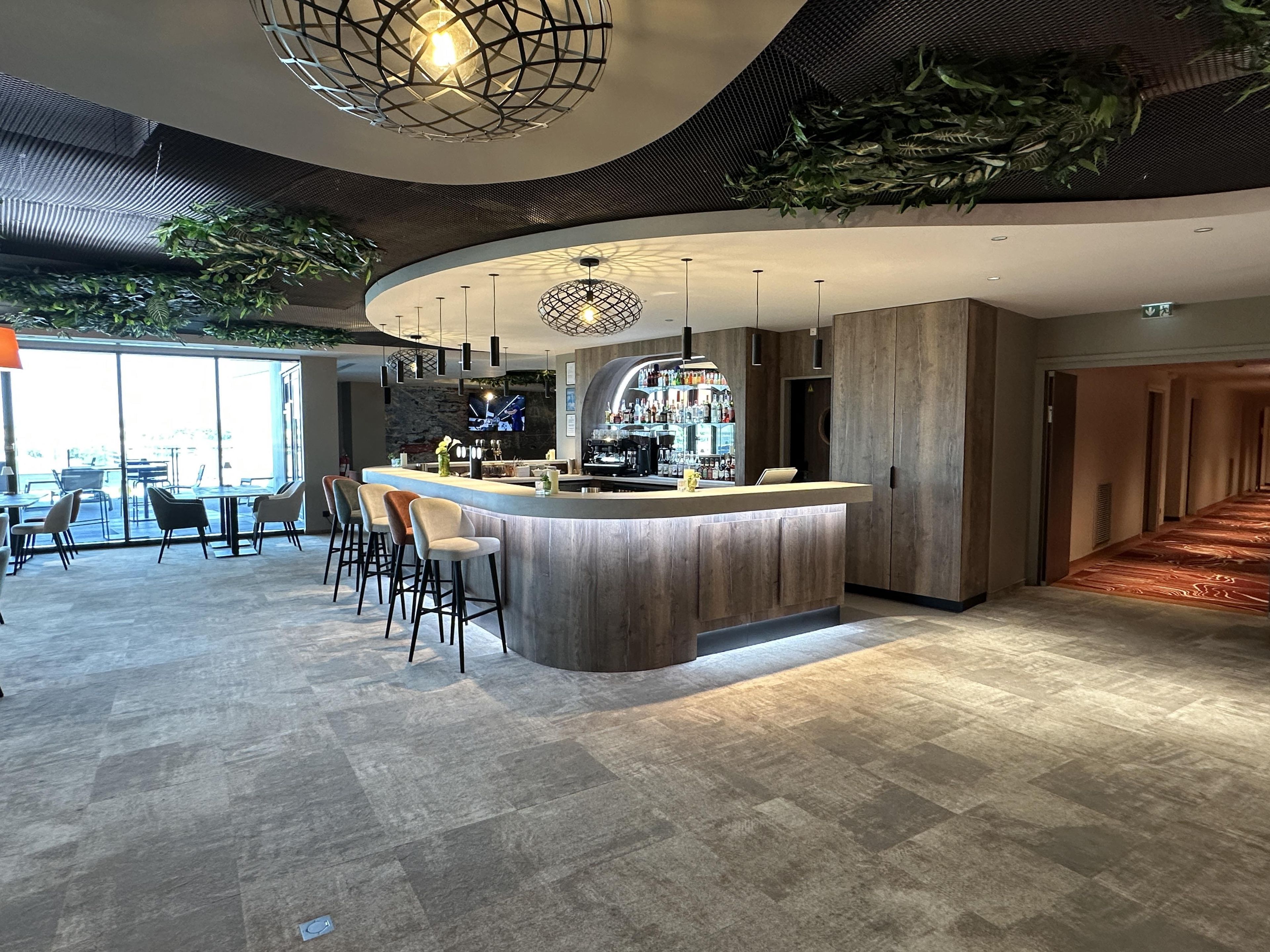 A modern bar area with a curved counter, bar stools, and a television screen.