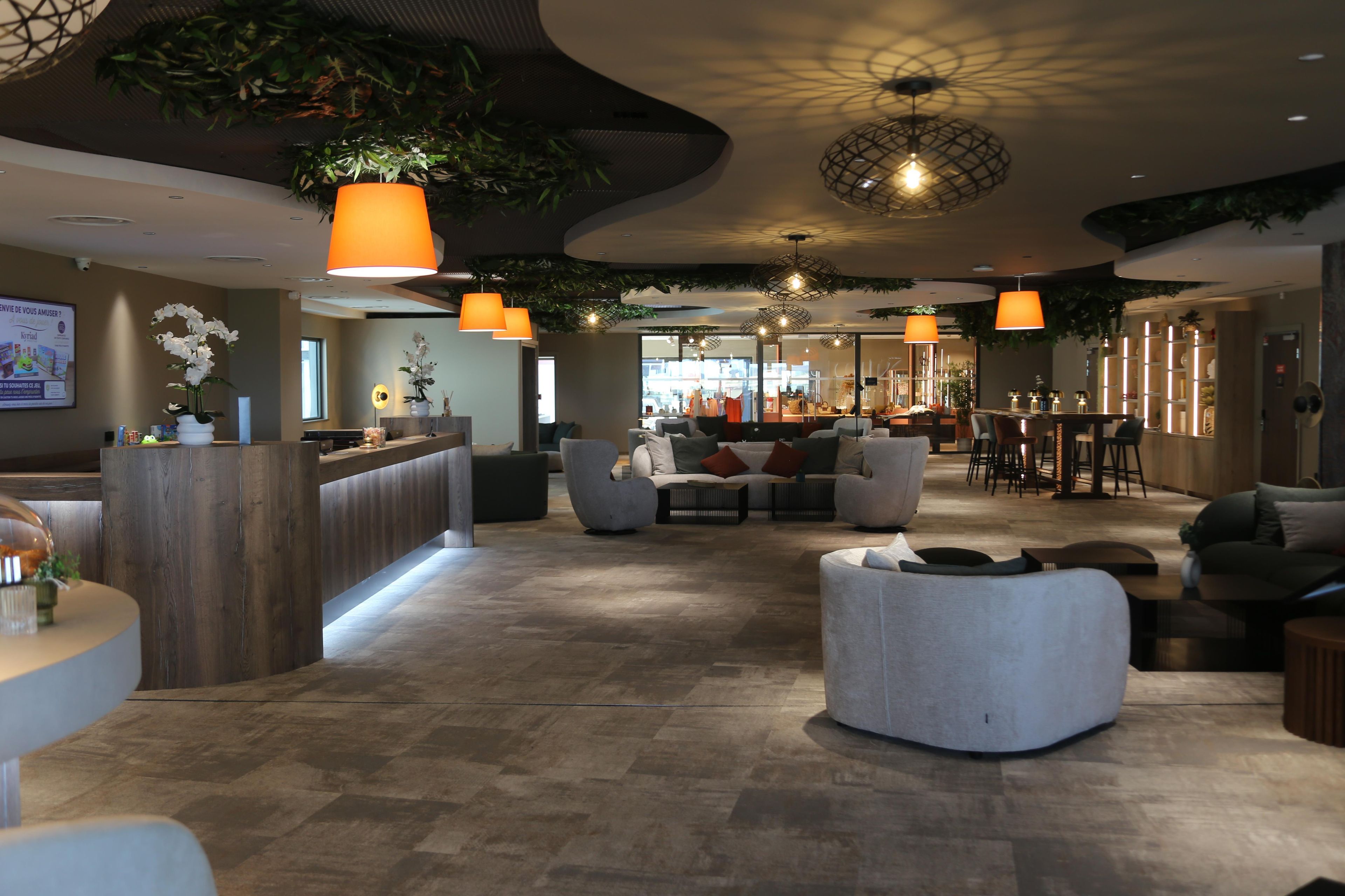 A modern hotel lobby with a reception desk, seating area, and bar.