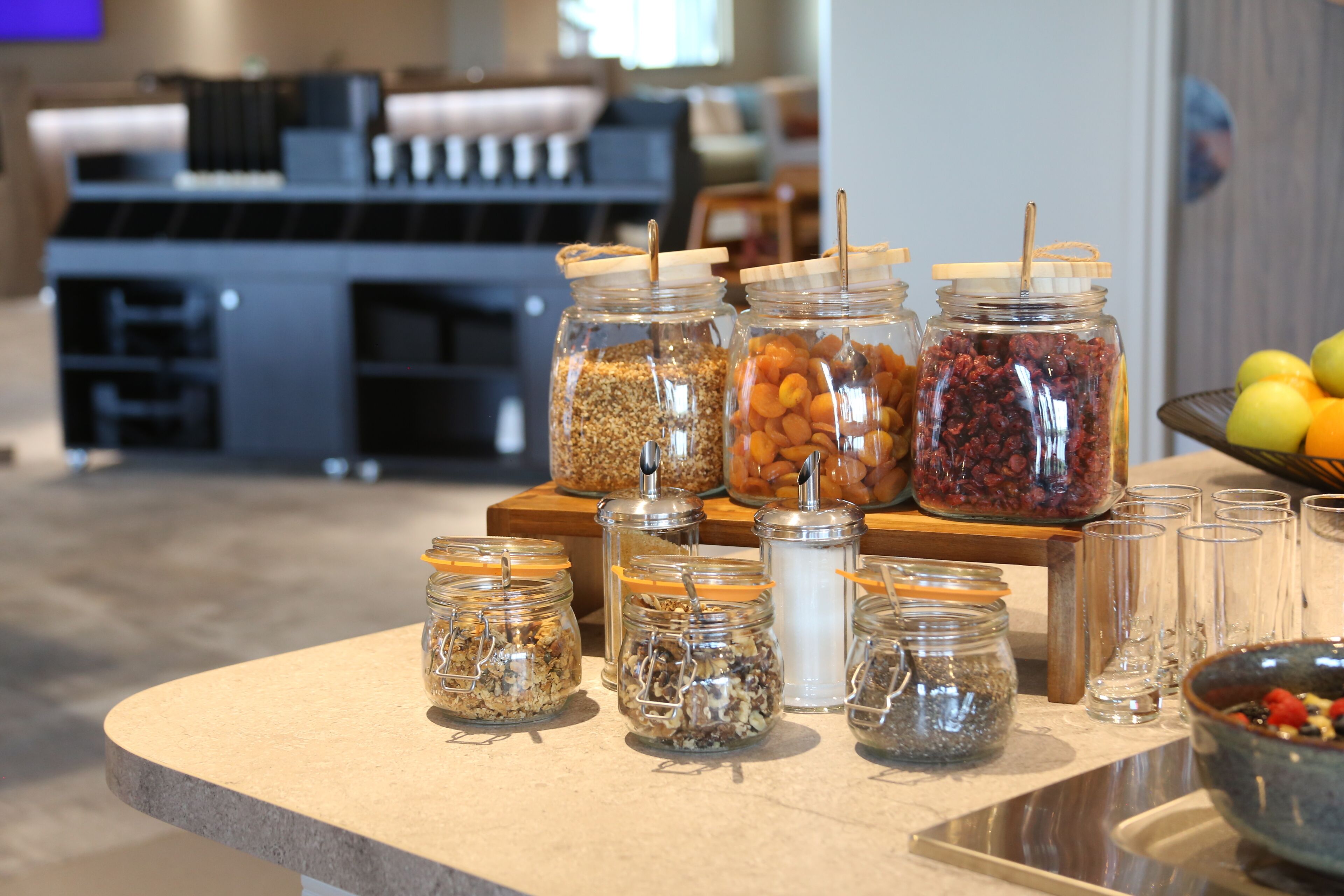 A buffet area with various food items in glass jars and a fruit bowl.